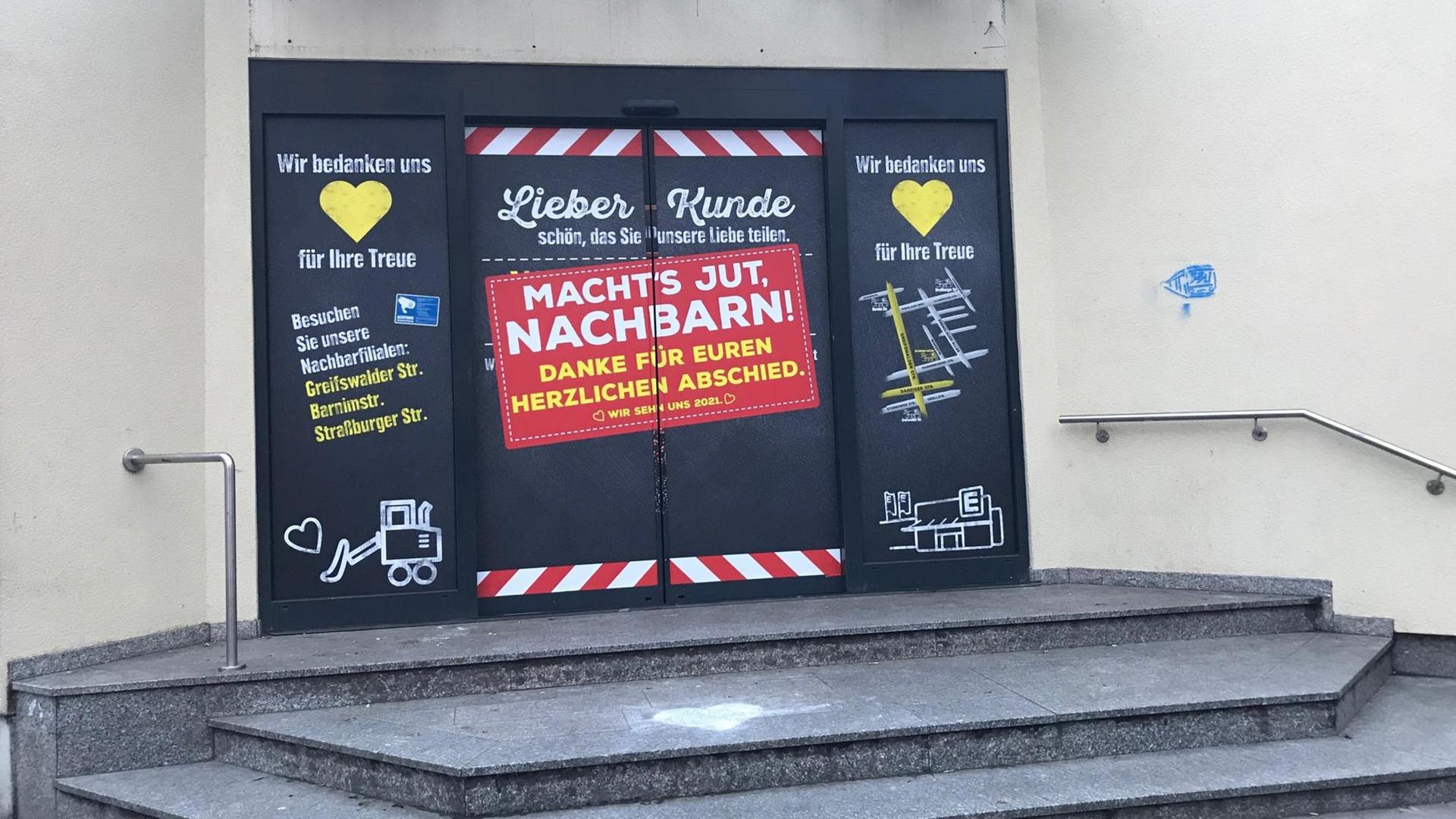 Eine geschlossene Supermarkttür, auf der als Schild "Macht's Jut, Nachbarn" steht. Eine geschlossene Supermarkttür, auf der als Schild "Macht's Jut, Nachbarn" steht.