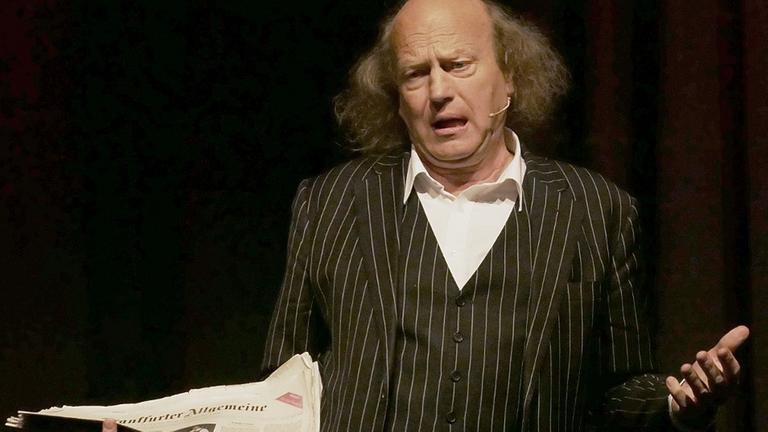 Ehrenpreisräger Arnulf Rating bei seinem Auftritt mit Zeitung in der Hand. Ehrenpreisräger Arnulf Rating bei seinem Auftritt mit Zeitung in der Hand.
