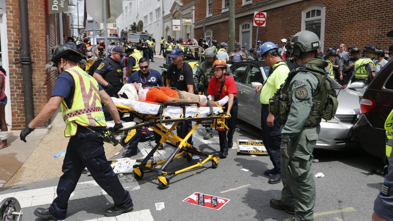 Helfer versorgen verletzte Menschen nachdem ein Auto in Gegendemonstranten in Charlottesville gefahren ist. Helfer versorgen verletzte Menschen nachdem ein Auto in Gegendemonstranten in Charlottesville gefahren ist.