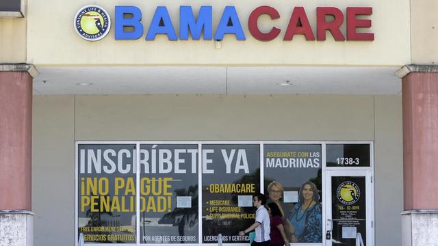 Eine Frau und ein Mann an einer Apotheke mit der Aufschrift "Obamacare" vorbei