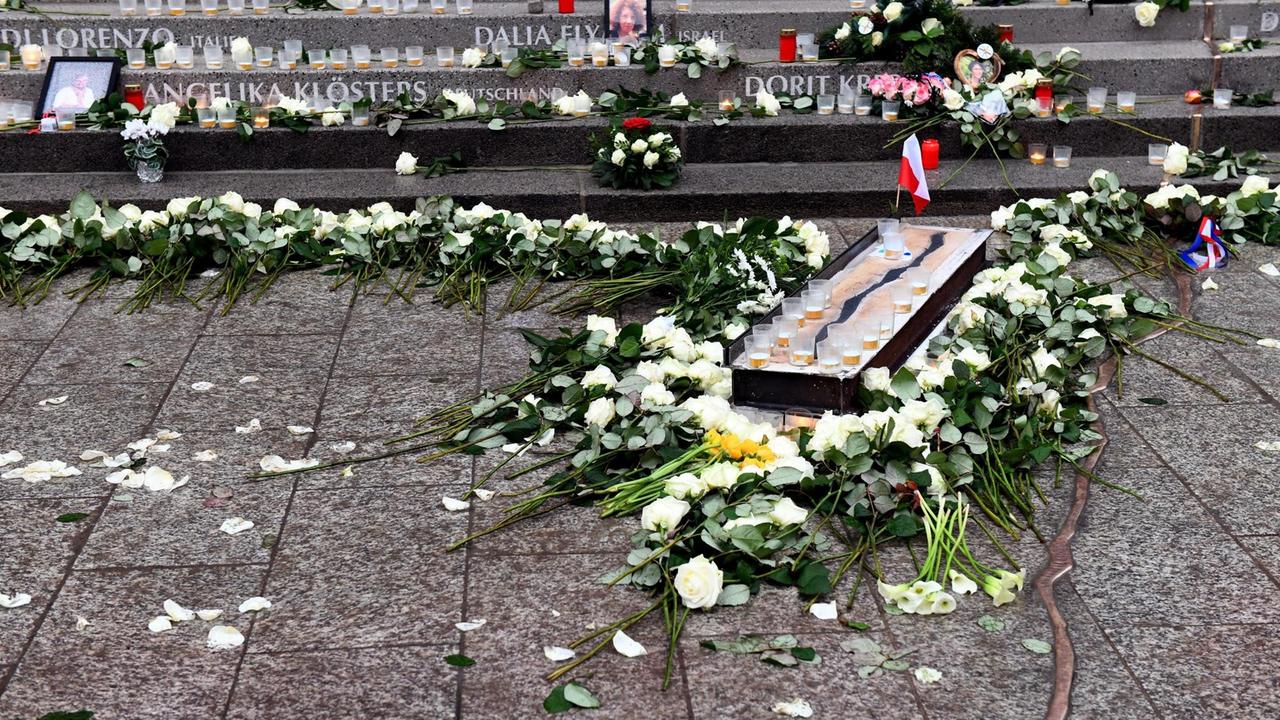 Blumen und Kerzen sind rund um das Mahnmal, einen bronzenen Riss im Boden, auf dem Breitscheidplatz in Berlin aufgestellt.