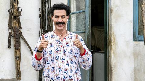 Szene aus dem neuen Borat-Film: Sacha Baron Cohen trägt einen Micky-Maus-Pyjama und blickt grinsend in die Kamera, beide Hände zeigen ein "Daumen hoch"