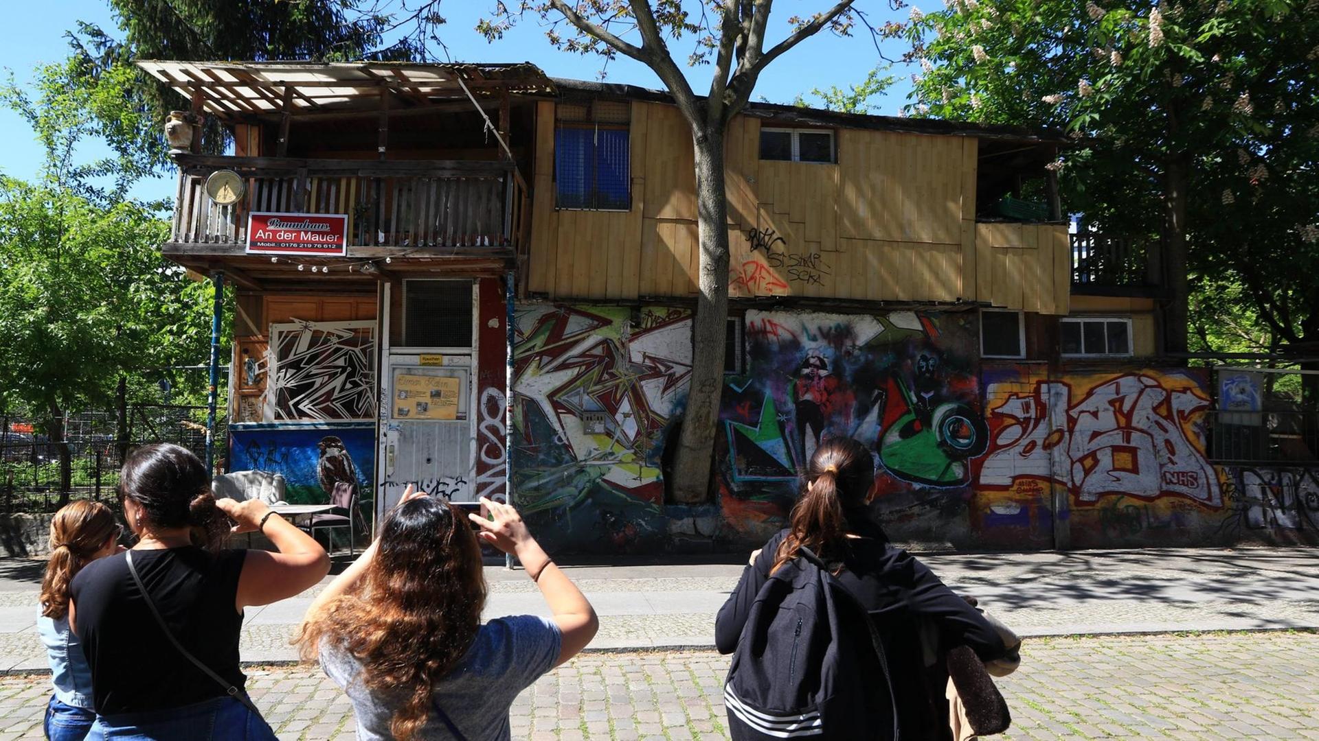 Touristen fotografieren das Baumhaus von Osman Kalin an der ehemaligen Mauer am Bethaniendamm in Berlin-Kreuzberg.