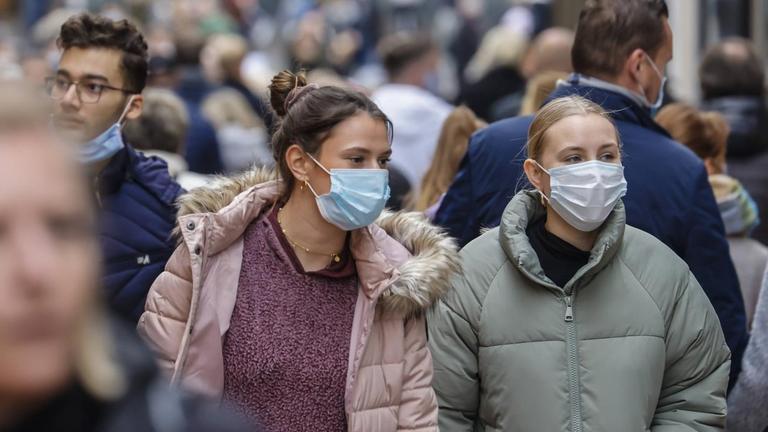 Jugendliche Passanten mit Schutzmasken gehen über eine weihnachtlich geschmückte Straße in Essen. Jugendliche Passanten mit Schutzmasken gehen über eine weihnachtlich geschmückte Straße in Essen.