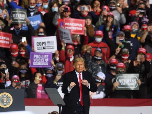 Präsident Trump bei einer Wahlkampfveranstaltung in Johnstown, Pennsylvania. Im Hintergrund Anhängerinnen mit Bannern.
