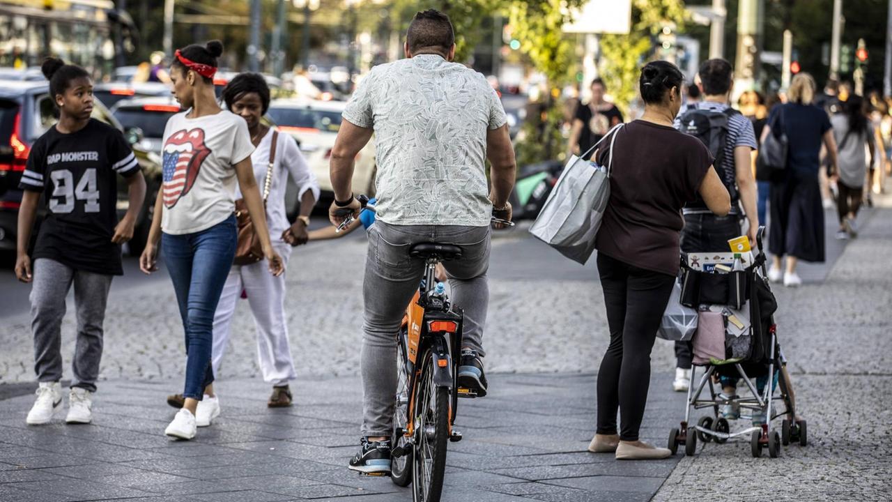 Ein Fahrradfahrer fährt auf einem Gehweg zwischen Passanten in Berlin-Kreuzberg.