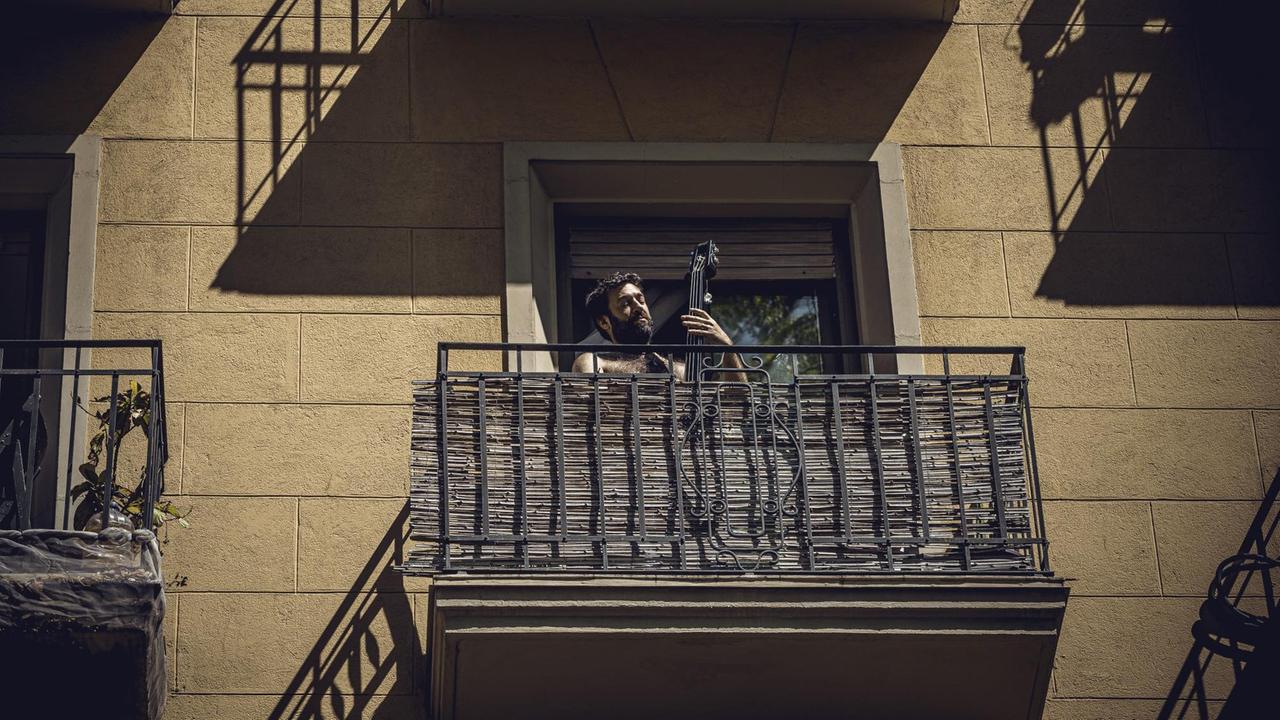 Ein Mann spielt Bass auf einem Balkon in Barcelona.