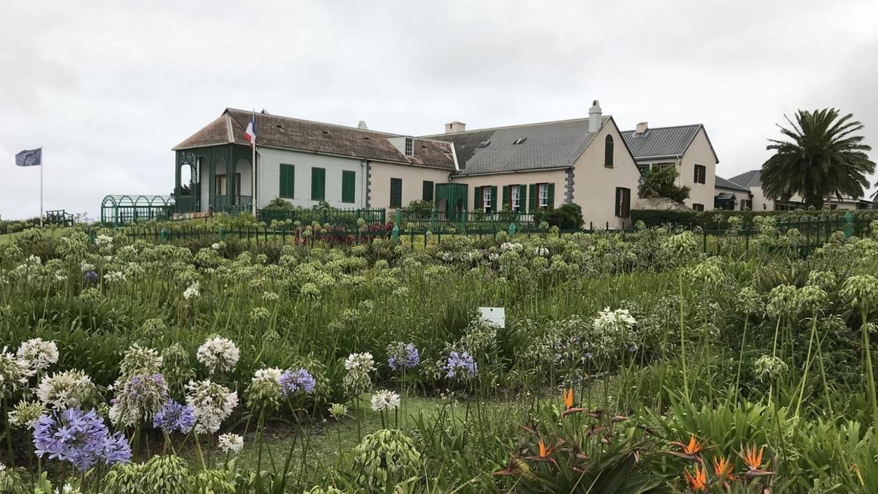 Longwood House - hier lebte Napoleon sechs Jahre in Verbannung bis zum Tod 1821. Grüner Garten und großes Holzhaus mit wehender französischer und EU-Fahne.