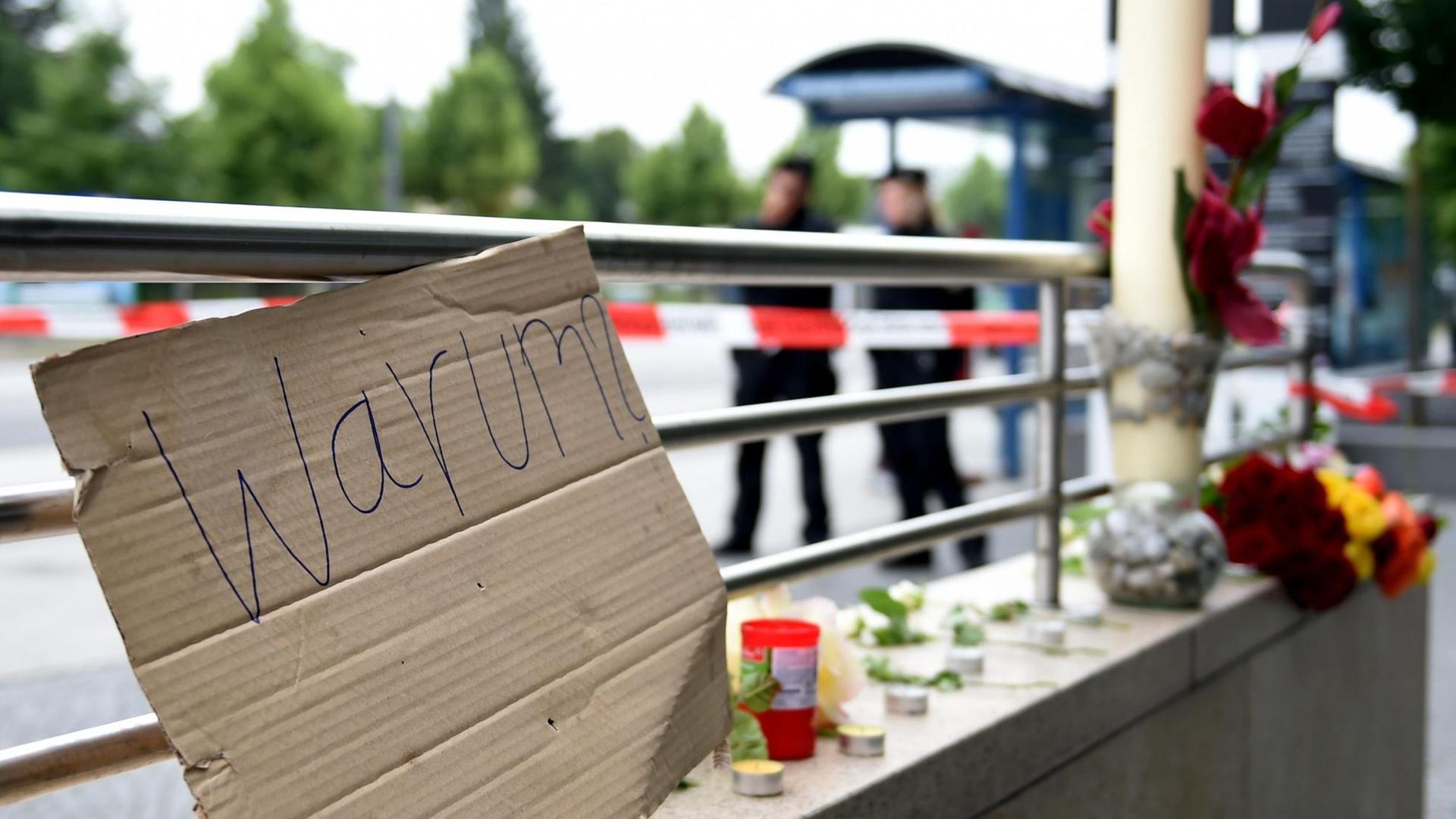 Ein Pappschild mit der Aufschrift "Warum?" und Blumen liegen am Eingang der U-Bahn "Olympia Einkaufszentrum" in München. Ein Pappschild mit der Aufschrift "Warum?" und Blumen liegen am Eingang der U-Bahn "Olympia Einkaufszentrum" in München.