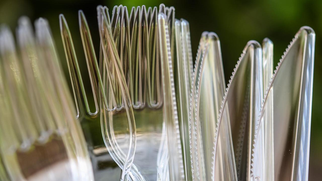 Messer und Gabeln aus Plastik stehen in einem Kunststoffbecher Messer und Gabeln aus Plastik stehen in einem Kunststoffbecher