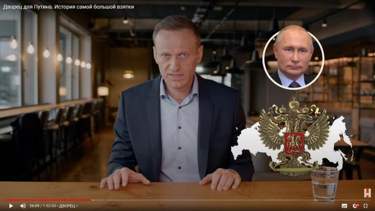Im Video ist der Oppositionspolitiker Aleksej Nawalny zu sehen, der ein Bild von Wladimir Putin zeigt. Im Video ist der Oppositionspolitiker Aleksej Nawalny zu sehen, der ein Bild von Wladimir Putin zeigt.