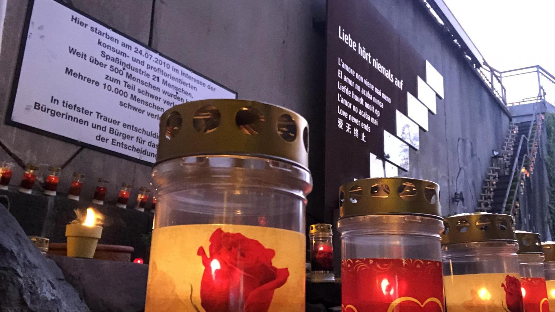 Dicke, weiße Friedhofskerzen, auf denen Herzen oder Rosen- und Orchideen-Blüten abgedruckt sind, stehen vor und auf der Gedenkstätte in Duisburg. Dort kamen am am 24. Juli 2010 21 Menschen ums Leben. Dicke, weiße Friedhofskerzen, auf denen Herzen oder Rosen- und Orchideen-Blüten abgedruckt sind, stehen vor und auf der Gedenkstätte in Duisburg. Dort kamen am am 24. Juli 2010 21 Menschen ums Leben.