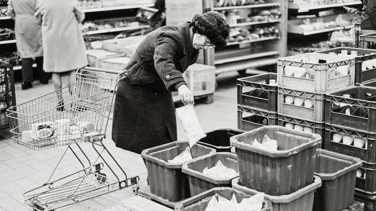 Eine Frau prüft Milchtüten in einer Kaufhalle in der DDR.
