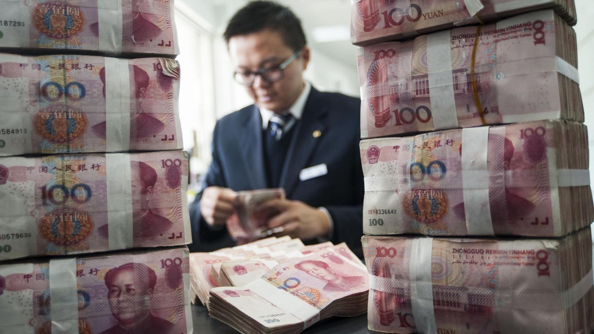 Ein chinesischer Bankmitarbeiter zählt Renminbi-Yuan-Geldscheine Ein chinesischer Bankmitarbeiter zählt Renminbi-Yuan-Geldscheine