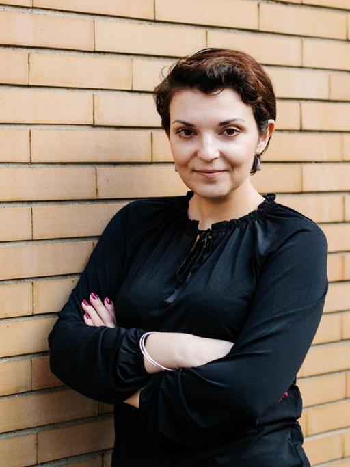 Porträt von Natalya Nepomnyashcha vor einer Backstein-Wand.