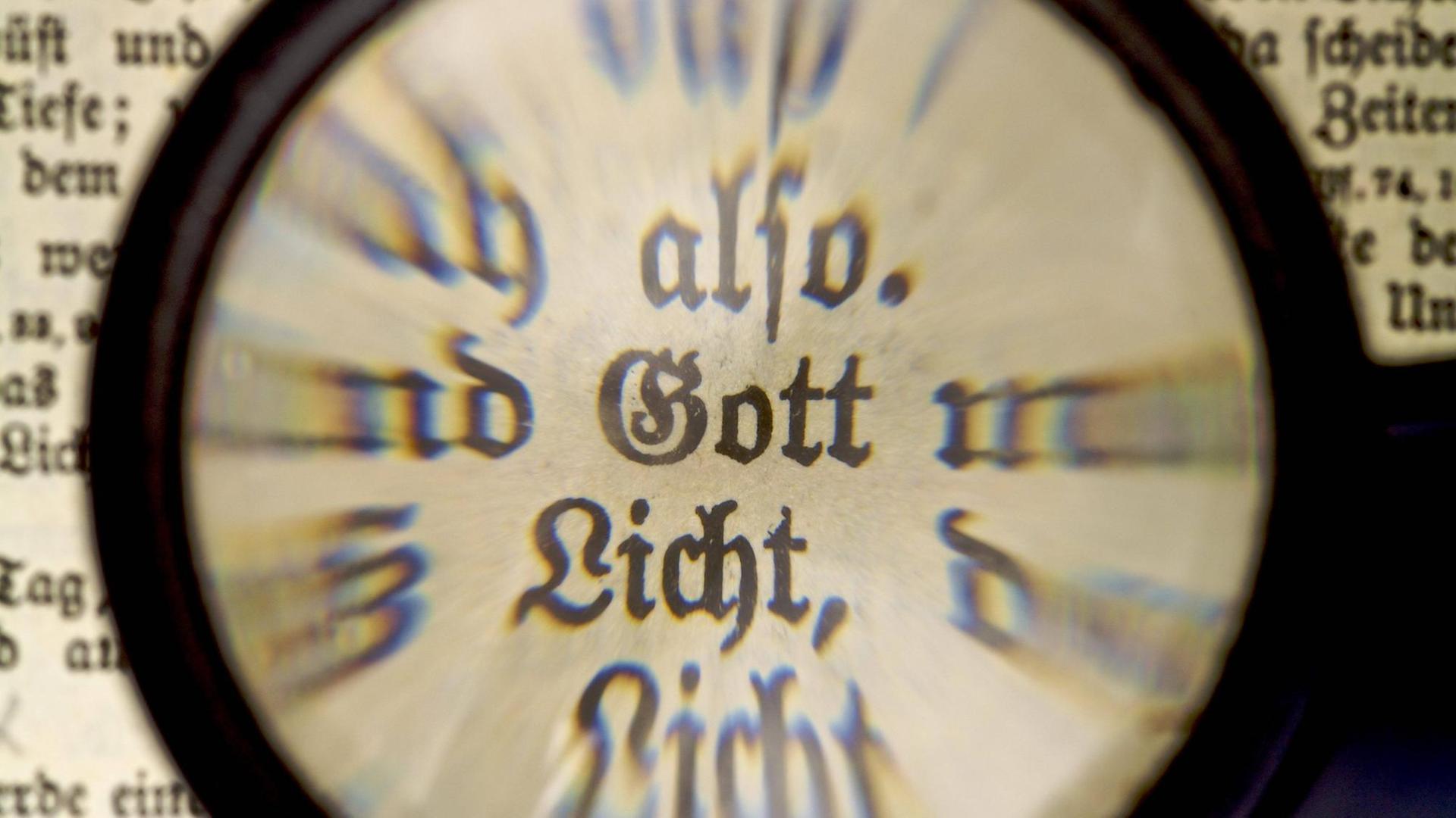 Das Wort Gott, durch eine Lupe in einer alten Bibel betrachtet Das Wort Gott, durch eine Lupe in einer alten Bibel betrachtet