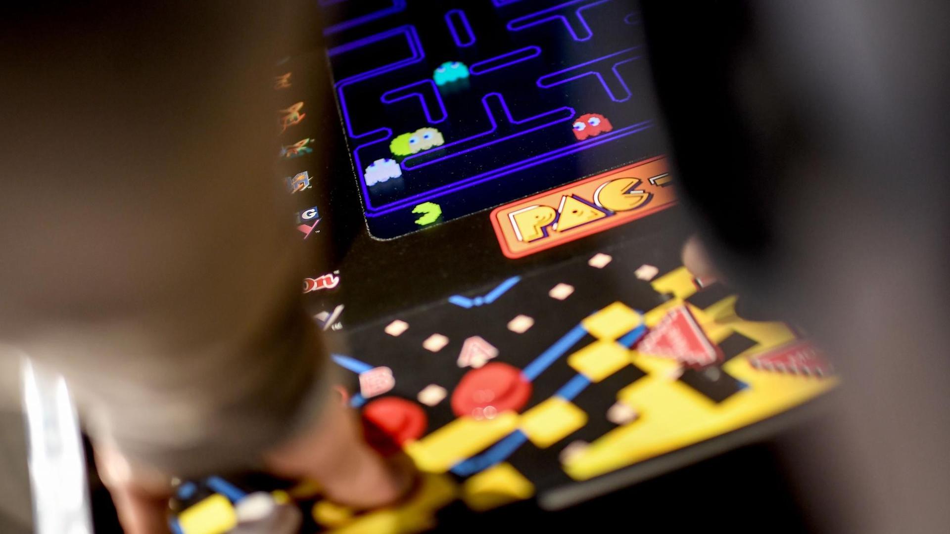 Ein junger Mann spielt das Computerspiel "Pac Man" an einem Automaten in der Ausstellung "Nineties Berlin" in der Alten Münze in Berlin. Ein junger Mann spielt das Computerspiel "Pac Man" an einem Automaten in der Ausstellung "Nineties Berlin" in der Alten Münze in Berlin.