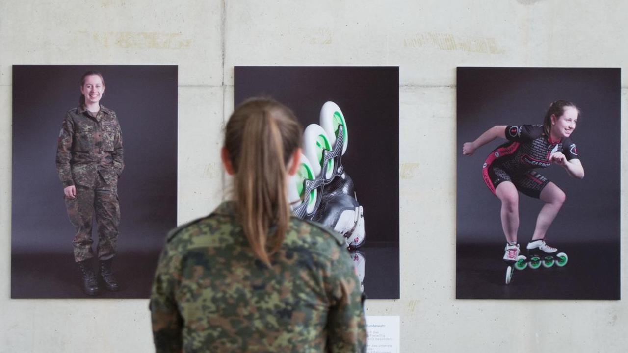 Die Gefreite Kristine Grahmann steht am 30.05.2017 vor Fotografien, die sie und einen weiteren Soldaten in Uniform und beim Sport zeigen. Die Gefreite Kristine Grahmann steht am 30.05.2017 vor Fotografien, die sie und einen weiteren Soldaten in Uniform und beim Sport zeigen.