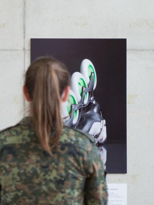 Die Gefreite Kristine Grahmann steht am 30.05.2017 vor Fotografien, die sie und einen weiteren Soldaten in Uniform und beim Sport zeigen.