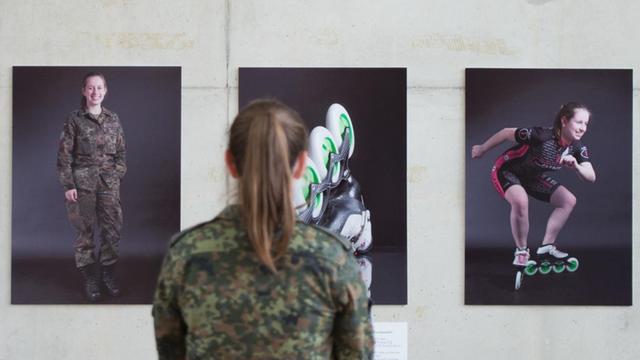 Die Gefreite Kristine Grahmann steht am 30.05.2017 vor Fotografien, die sie und einen weiteren Soldaten in Uniform und beim Sport zeigen.