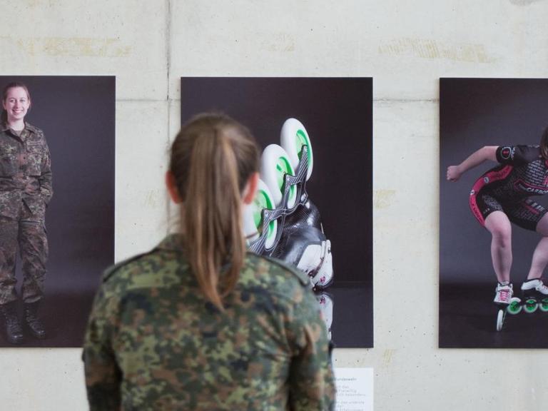 Die Gefreite Kristine Grahmann steht am 30.05.2017 vor Fotografien, die sie und einen weiteren Soldaten in Uniform und beim Sport zeigen.