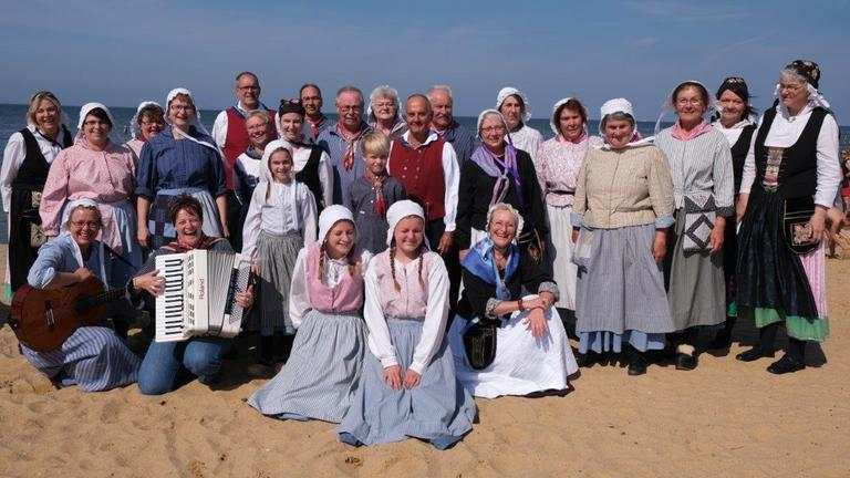 Gruppenbild des Chores in Trachten am Strand. Dahinter die Nordsee. Gruppenbild des Chores in Trachten am Strand. Dahinter die Nordsee.