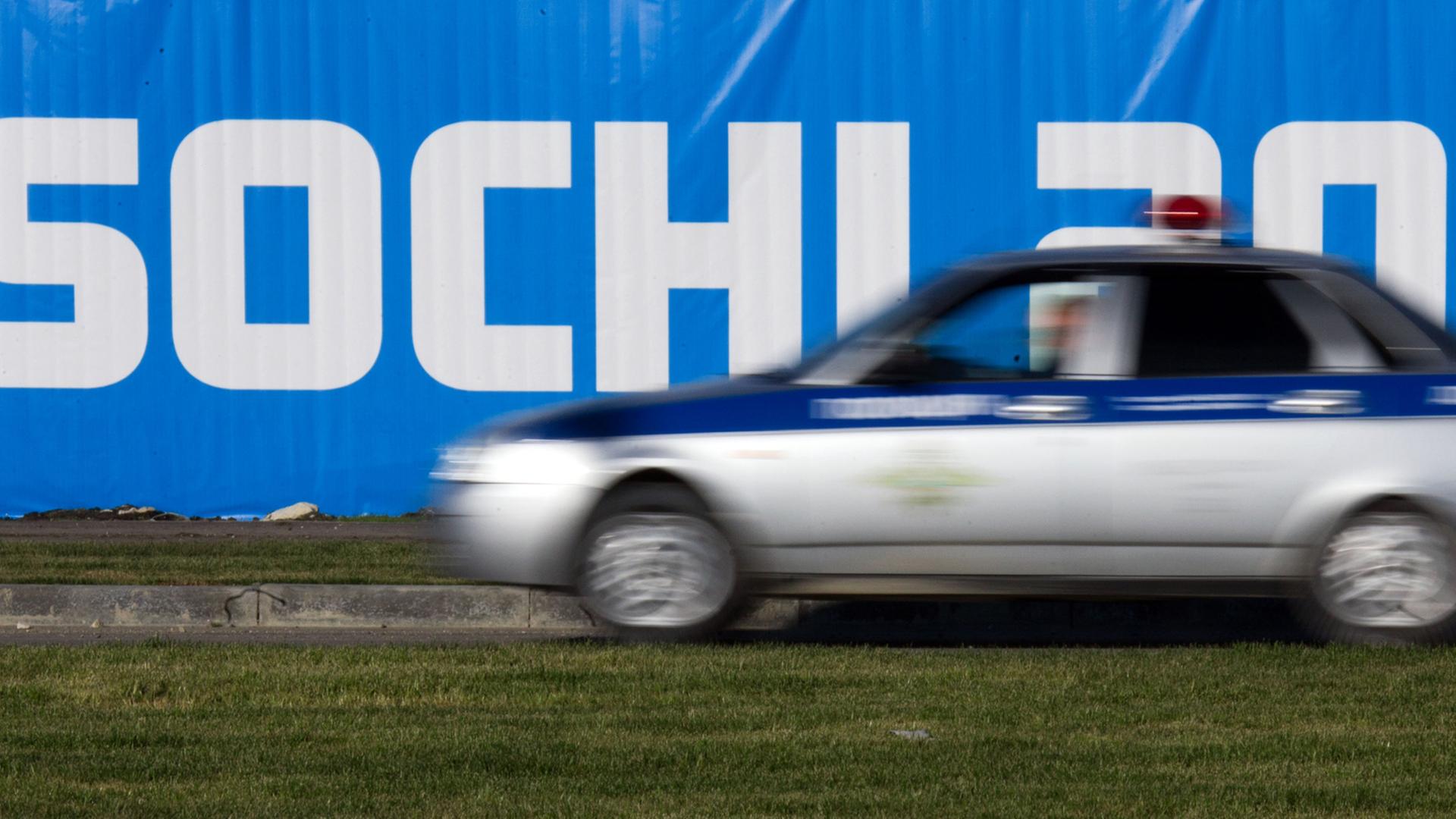 Ein Polizeiauto fährt in der Nähe des Olympischen Park im russischen Sotschi direkt am Schwarzen Meer an einem Werbebanner mit dem Schriftzug "Sochi 2014" vorbei. Ein Polizeiauto fährt in der Nähe des Olympischen Park im russischen Sotschi direkt am Schwarzen Meer an einem Werbebanner mit dem Schriftzug "Sochi 2014" vorbei.