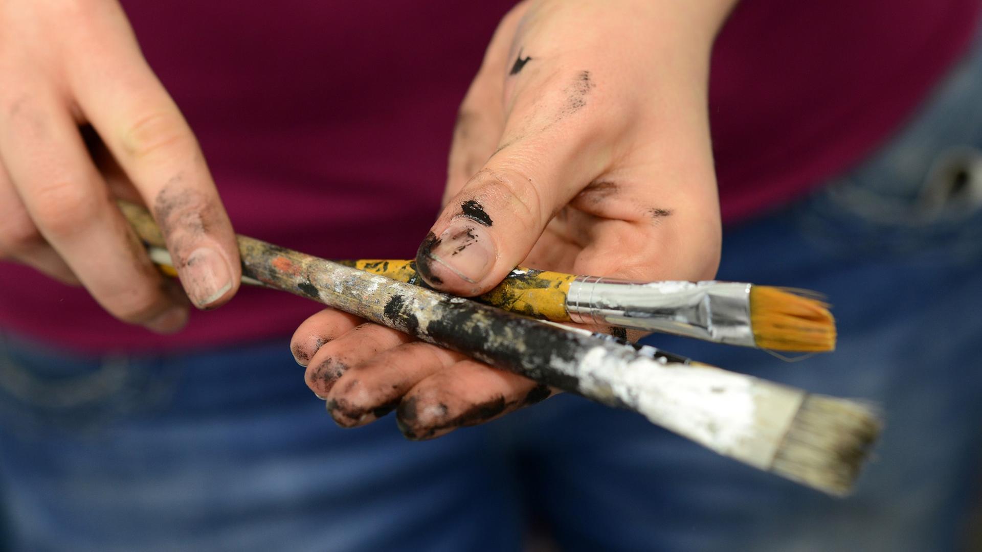 Zwei Hände halten zwei Malpinsel. Zwei Hände halten zwei Malpinsel.