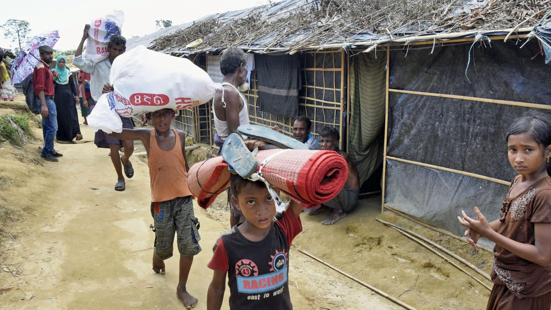 Geflüchtete Rohingya tragen in einem Camp in Cox's Bazaar im Südosten von Bangladesch verteilte Hilfsgüter. Geflüchtete Rohingya tragen in einem Camp in Cox's Bazaar im Südosten von Bangladesch verteilte Hilfsgüter.