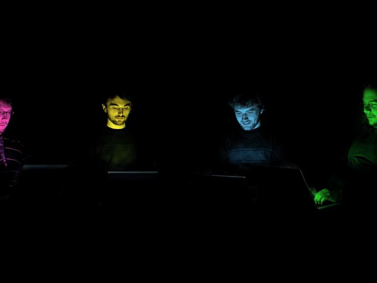Die Gesichter der Mitglieder der Band "Benoît and the Mandelbrots" bunt ausgeleuchtet vor schwarzem Hintergrund