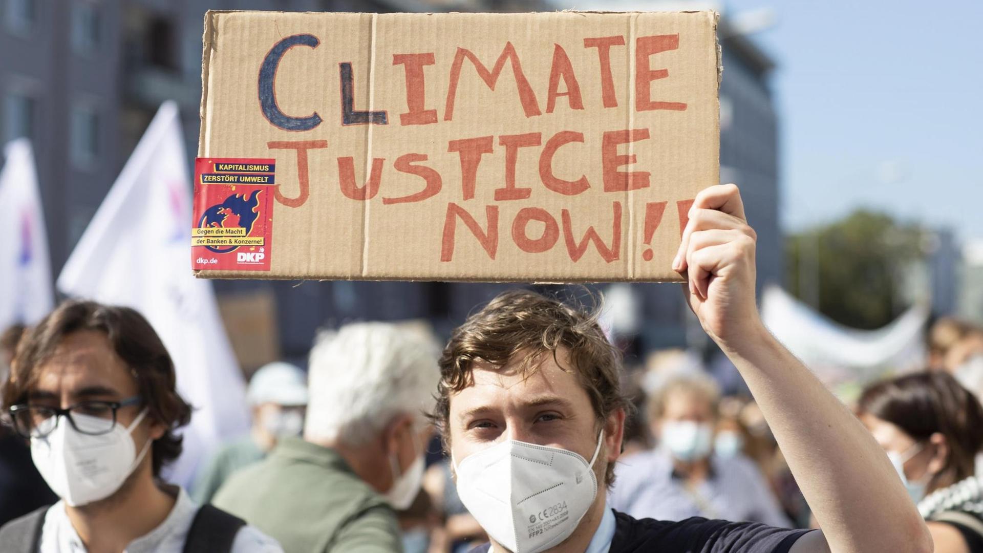 Fridays for future Demonstration gegen Klimawandel. Ein Jugendlicher hält ein Pappschild mit der Aufschrift "Climate Justice" hoch. Fridays for future Demonstration gegen Klimawandel. Ein Jugendlicher hält ein Pappschild mit der Aufschrift "Climate Justice" hoch.