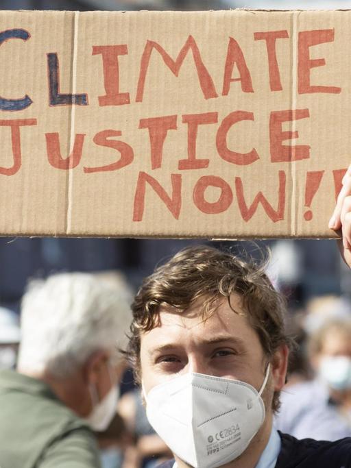 Fridays for future Demonstration gegen Klimawandel. Ein Jugendlicher hält ein Pappschild mit der Aufschrift "Climate Justice" hoch.