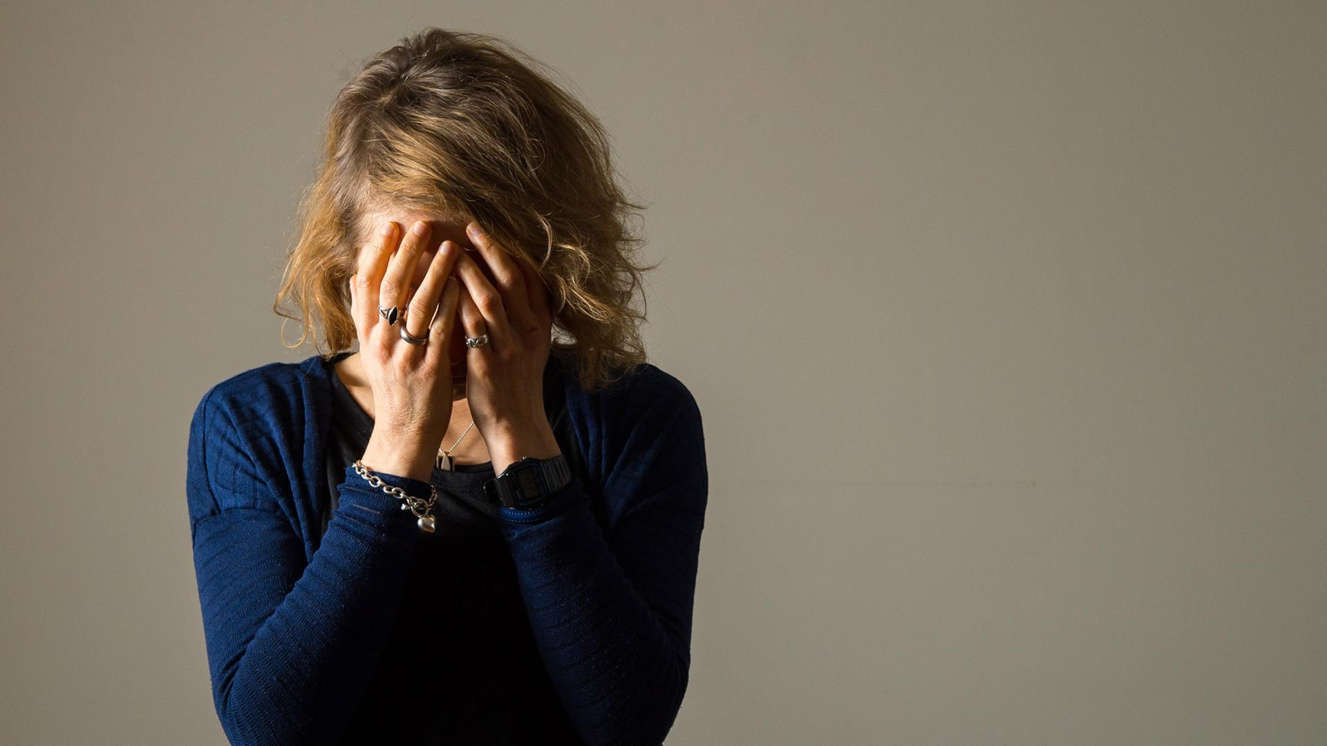 Eine Frau, die die Hände vor das Gesicht hält, der Kopf ist geneigt. Eine Frau, die die Hände vor das Gesicht hält, der Kopf ist geneigt.