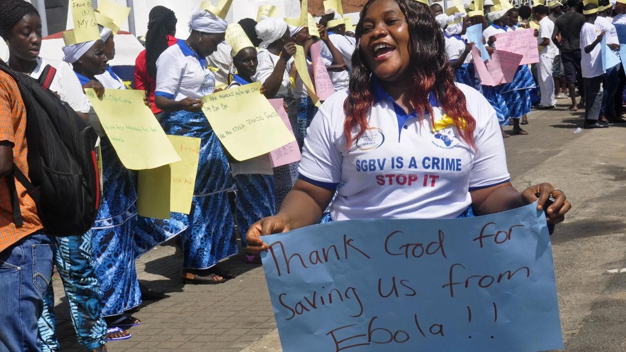 Eien Frau hält ein Schild mit der Aufschrift: "Danke Gott, dass er uns vor Ebola bewahrt hat."