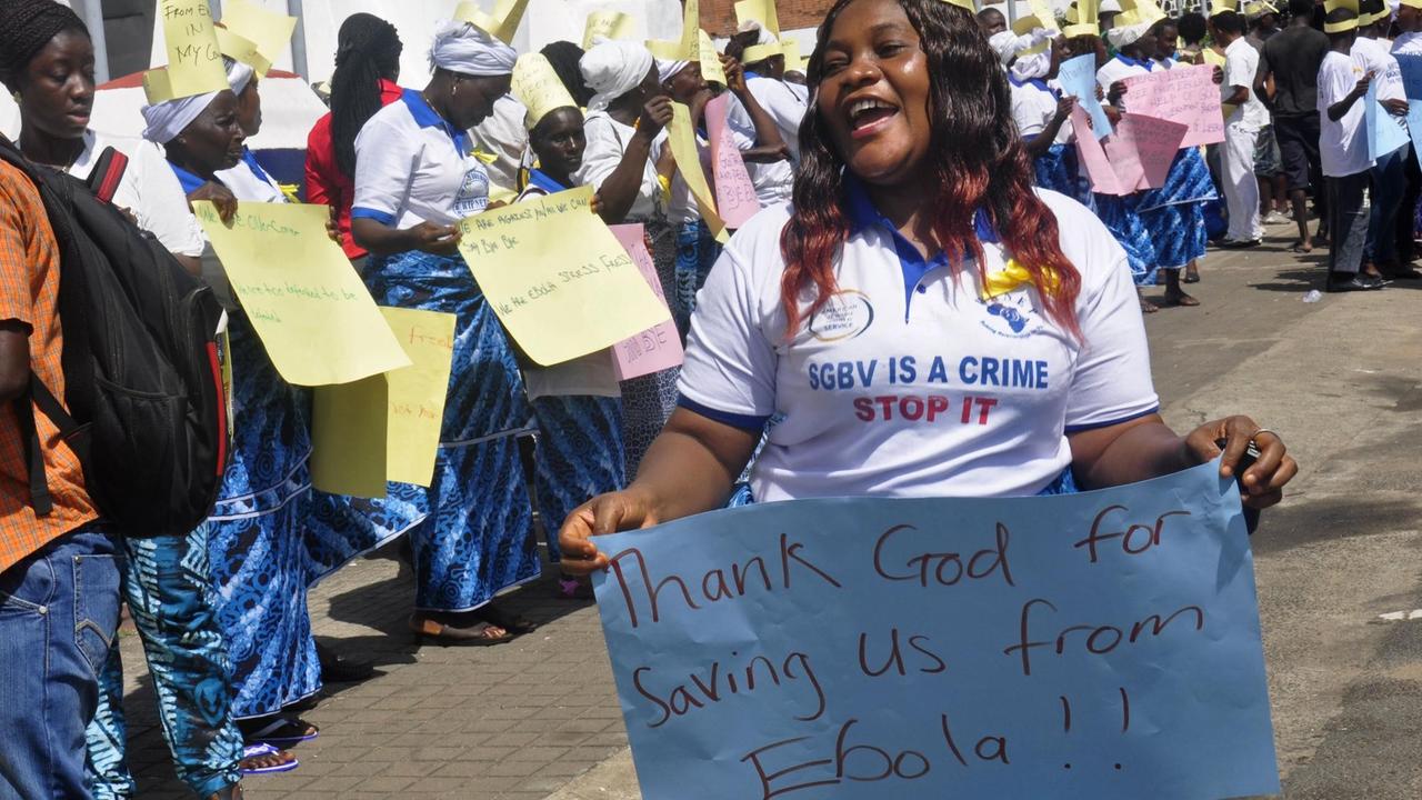Eien Frau hält ein Schild mit der Aufschrift: "Danke Gott, dass er uns vor Ebola bewahrt hat." Eien Frau hält ein Schild mit der Aufschrift: "Danke Gott, dass er uns vor Ebola bewahrt hat."