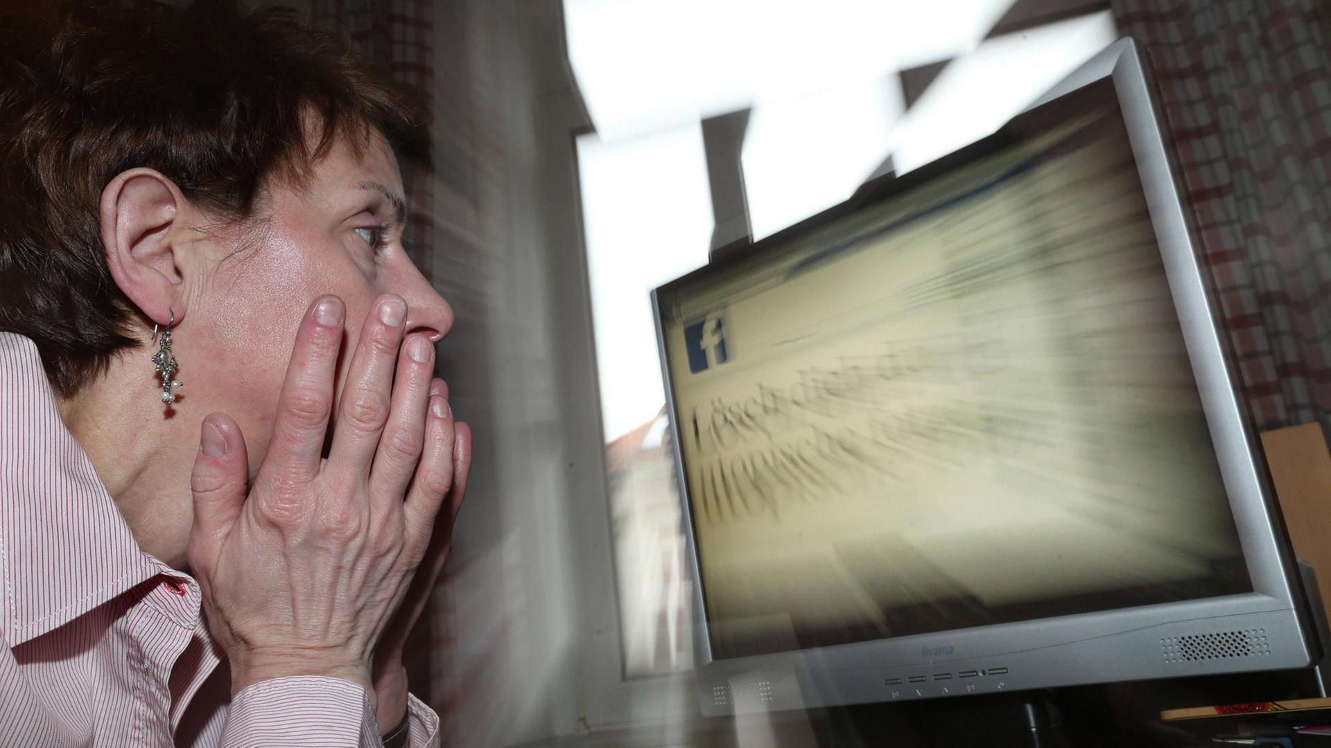 Frau vor einem Bildschirm mit Facebook-Logo Frau vor einem Bildschirm mit Facebook-Logo