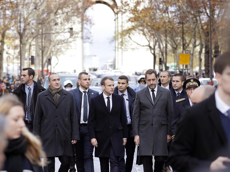 Emmanuel Macron (Mitte) und Innenminister Christophe Castaner (rechts) besichtigen am 2.12.18 den Triumphbogen in Paris nach den Krawallen vom Vortag.
