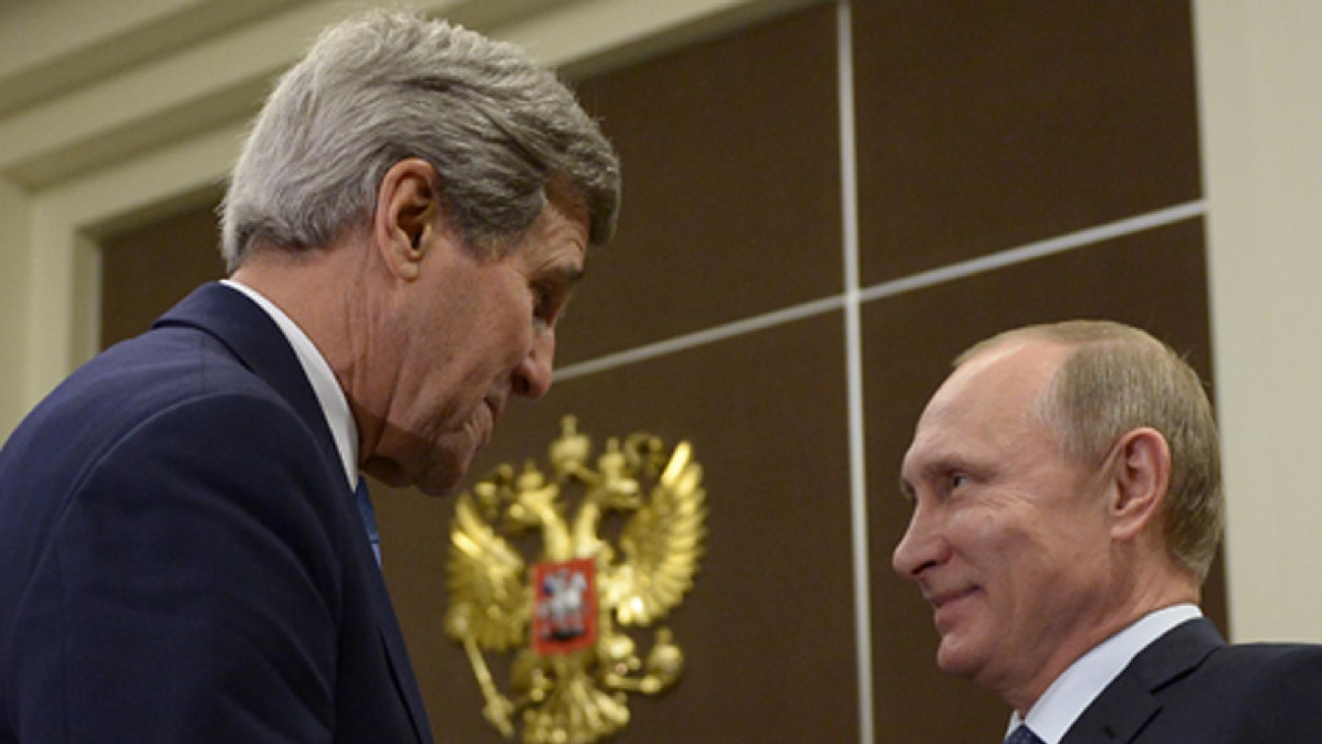 John Kerry und Wladimir Putin schütteln sich die Hände und lächeln sich an. John Kerry und Wladimir Putin schütteln sich die Hände und lächeln sich an.