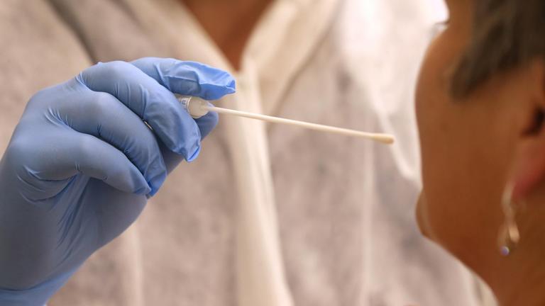 Ein Arzt nimmt in einer Hausarztpraxis mit einem Tupfer einen Abstrich bei einer Frau für einen Coronatest. Ein Arzt nimmt in einer Hausarztpraxis mit einem Tupfer einen Abstrich bei einer Frau für einen Coronatest.