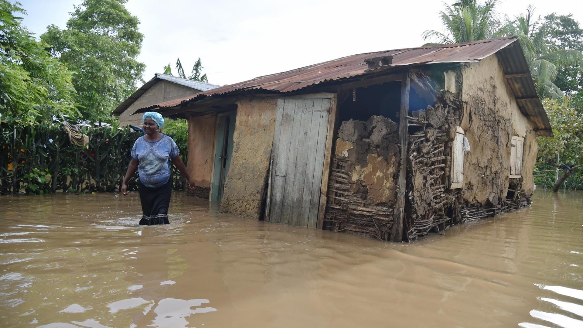 Eine Frau steht in Malfeti im Nordosten haitis knietief im Wasser vor ihrer überschwemmten Hütte.