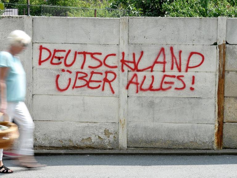 Ein Graffiti an einer Mauer mit der Aufschrift "Deutschland über alles" in roter Farbe.