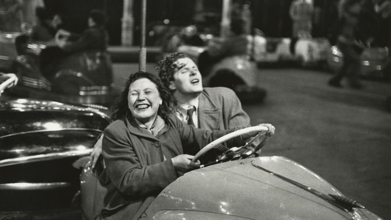 Eine Frau und ein Mann fahren freudestrahlend mit geschlossenen Augen Autoscooter. Die Fotografie ist schwarz-weiß. Eine Frau und ein Mann fahren freudestrahlend mit geschlossenen Augen Autoscooter. Die Fotografie ist schwarz-weiß.