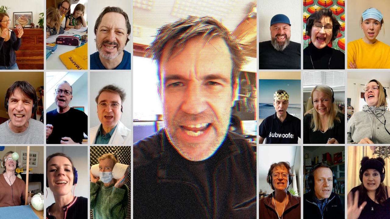 Screenshot eines Chormeetings, bei dem viele unterschiedliche Menschen zum Teil mit Kopfhörern singen. Screenshot eines Chormeetings, bei dem viele unterschiedliche Menschen zum Teil mit Kopfhörern singen.