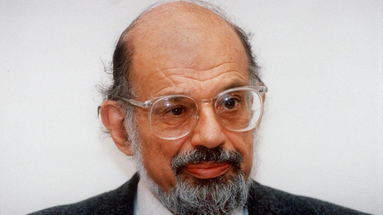 Der US-amerikanische Schriftsteller und Lyriker Allen Ginsberg, ein älterer Herr mit Stirnglatze und Brille.