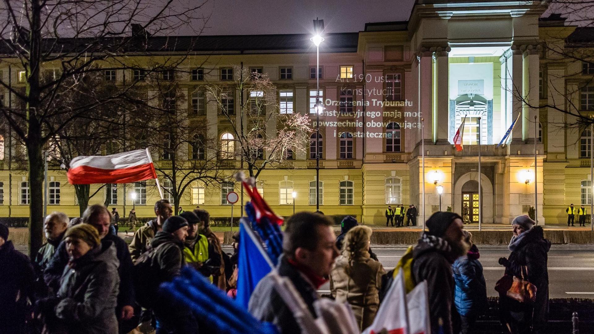 Demonstranten vor einem Gebäude, an das ein Text projiziert wurde. Demonstranten vor einem Gebäude, an das ein Text projiziert wurde.