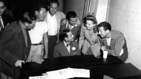 Cole Porter sitzt am Piano, um ihn herum stehen von links nach rechts Gregory Ratoff, Jack Oakie, Jaye Martin, William Gaxton, Janet Blair und Don Ameche