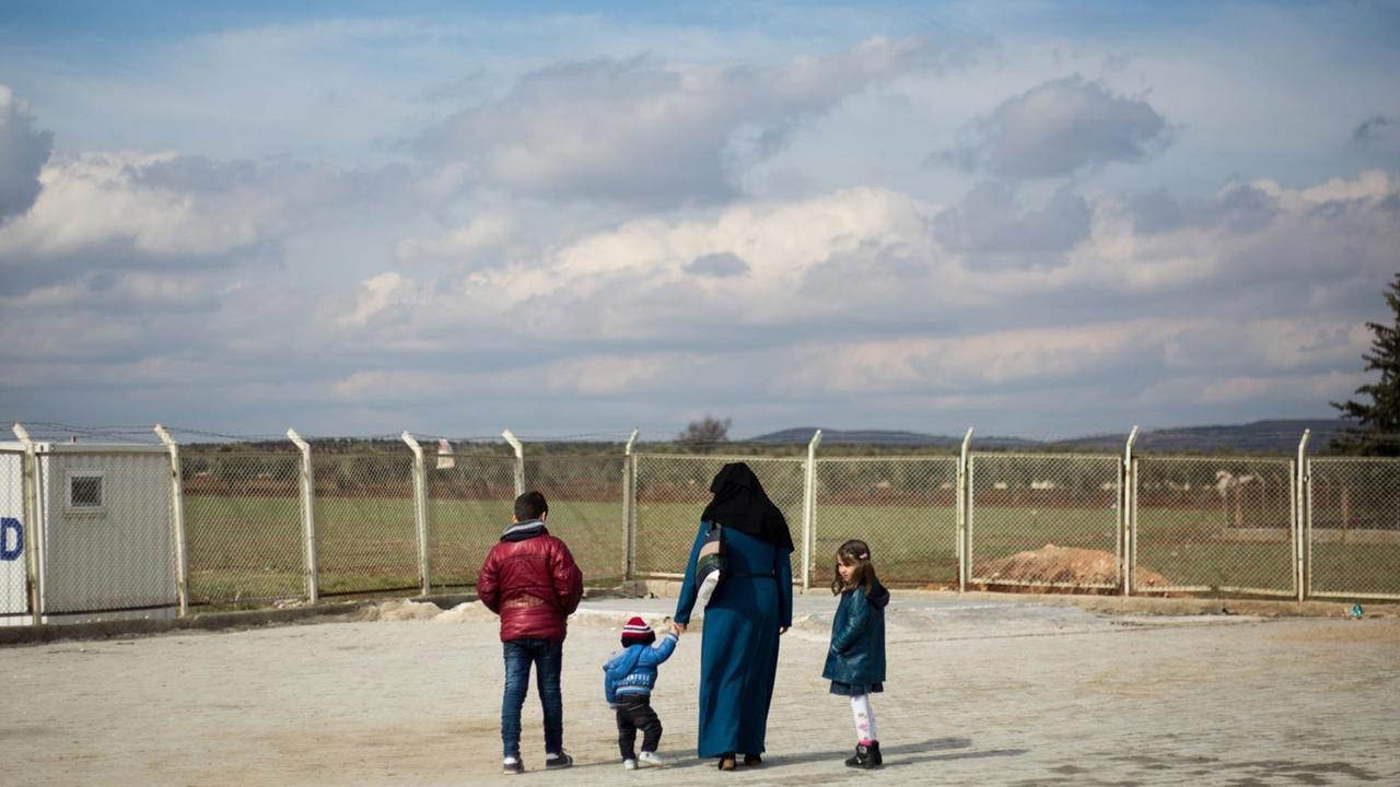 Eine syrische Flüchtlingsfamilie steht am Grenzzaun zum Nachbarland Türkei in der Nähe der türkischen Stadt Kilis Eine syrische Flüchtlingsfamilie steht am Grenzzaun zum Nachbarland Türkei in der Nähe der türkischen Stadt Kilis