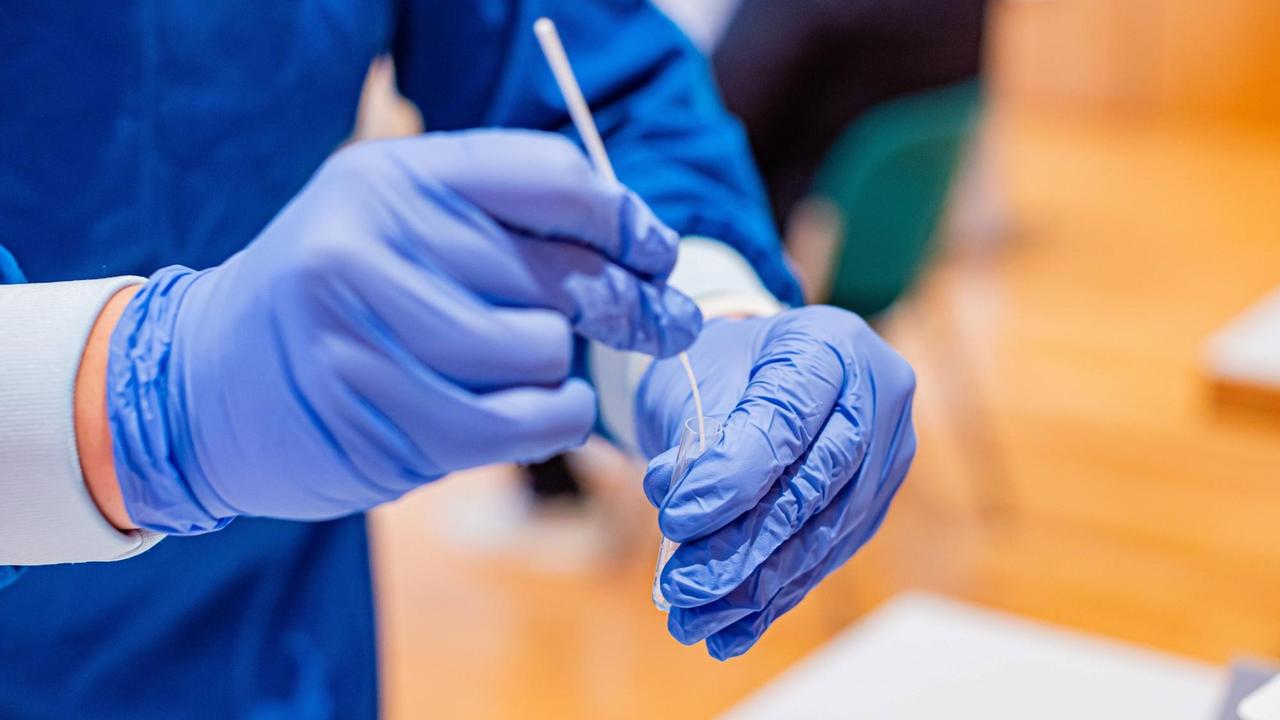 Eine Person mit Gummihandschuhen hält einen Corona-Schnelltest in den Händen Eine Person mit Gummihandschuhen hält einen Corona-Schnelltest in den Händen