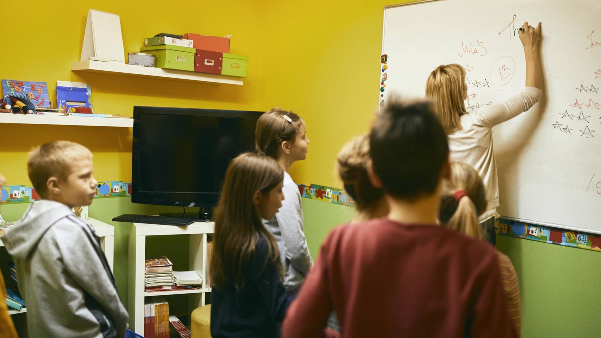Ein Lehrer schreibt auf ein Whiteboard. Ein Lehrer schreibt auf ein Whiteboard.