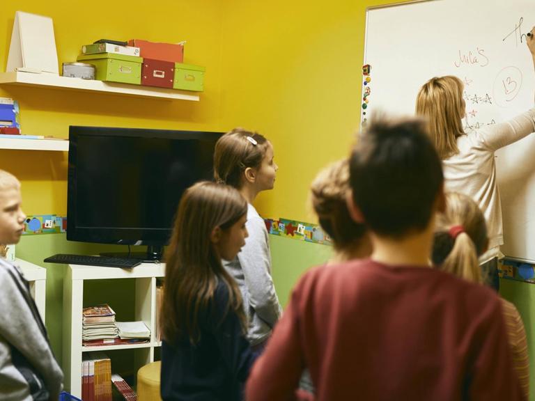 Ein Lehrer schreibt auf ein Whiteboard.
